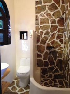 a bathroom with a toilet and a stone wall at Under the Tuscan Sun Cottage in West Los Angeles in Los Angeles