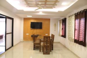 a dining room with a table and a tv on the wall at Malhar Bungalow in Panchgani