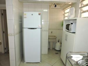 a white refrigerator in a small kitchen at Condomínio Adriático in Guarujá
