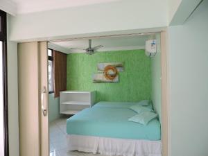 a bedroom with a bed with a green wall at Condomínio Lester Primo in Guarujá