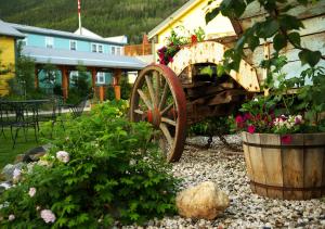 un vecchio carro di legno con fiori in giardino di Westmark Inn Dawson City a Dawson City
