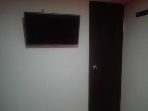 TV de pantalla plana en una pared junto a una puerta en Hotel Royal Center, en Pasto