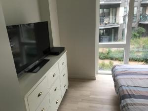 a bedroom with a dresser with a flat screen tv on it at Home Stay Marmormolen (Marmorvej) in Copenhagen