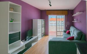 a living room with purple walls and a couch and a tv at Apto Playa de Coira in Portosin