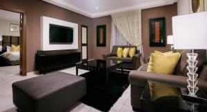 ein Wohnzimmer mit 2 Sofas und einem TV in der Unterkunft Oak Plaza Suites in Kumasi