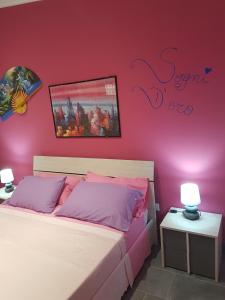 a bedroom with two beds and a pink wall at L'infinito Verde in Floridia