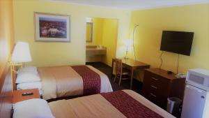 a hotel room with two beds and a desk and a television at Roadway Inn Troy in Troy
