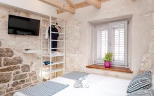um quarto com uma cama e uma televisão numa parede de pedra em Successus Old Town House em Hvar