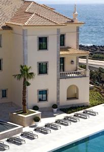 a villa with a swimming pool and the ocean at Grande Real Villa Itália Hotel & Spa in Cascais
