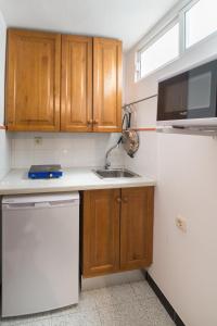 Una pequeña cocina con gabinetes de madera y un fregadero. en Coqueto estudio, en Cádiz