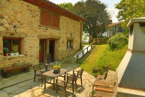 a table and chairs in front of a stone house at Alojamiento Rural Goierri in Barrika