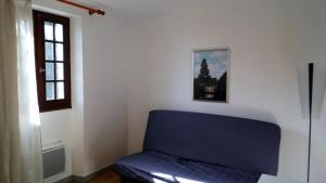 - un canapé bleu dans une chambre avec fenêtre dans l'établissement Gîte au calme avec point de vue proche Turenne, à Sarrazac