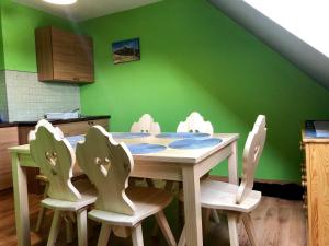 a table and chairs in a kitchen with a green wall at Apartamenty "U Bańki" in Kluszkowce