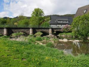 eine Brücke über einen Fluss mit einem Haus im Hintergrund in der Unterkunft Ferienwohnung Gerstmann in Wenholthausen