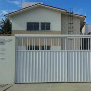 a white house with a gate and a fence at Verona in Paulista
