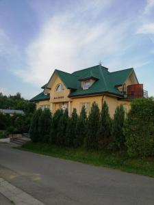 ein großes gelbes Haus mit grünem Dach in der Unterkunft Rajsko in Polańczyk