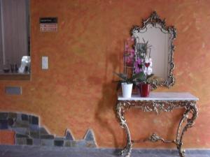 an orange wall with a mirror and a table with flowers at La Santre Villa in Amoudara Herakliou