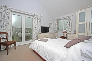PorthtowanにあるSea Otterの白いベッドルーム(大型ベッド1台、窓付)