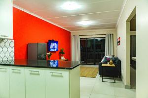 a kitchen with red walls and a black counter top at The Living Collective Apartments in Pietermaritzburg