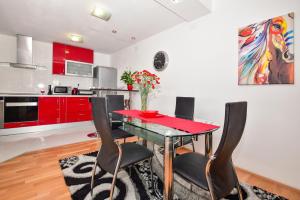 Apartment G.V. في ماكارسكا: مطبخ مع دواليب حمراء وطاولة مع كراسي