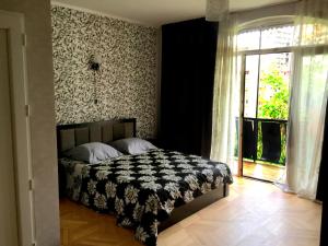a bedroom with a bed with a black and white blanket at GNT+ in Tbilisi City