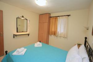 a bedroom with a blue bed and a mirror at Katerina Apartments in Pefkohori