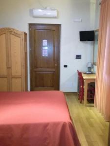1 dormitorio con cama roja y puerta de madera en Albergo Arinde, en Rende