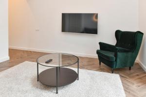 ボーソレイユにあるLuxury Studio next to Monte Carloのリビングルーム(ガラスのコーヒーテーブル、緑の椅子付)