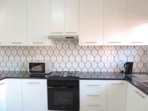 a kitchen with white cabinets and a black stove top oven at The Living Collective Apartments in Pietermaritzburg