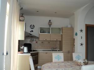 una cocina con armarios de madera, mesa y sillas en Villino dei Coralli en Lido di Ostia