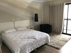 Un dormitorio con una gran cama blanca y una ventana en Hayer Hotel en Erechim