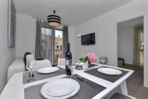 a white dining room table with white plates on it at Apartment Kate in Podgora