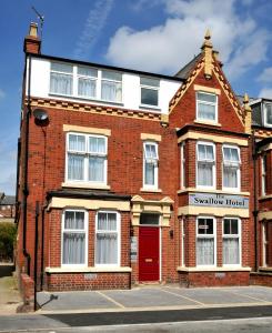 a brick building with a red door on a street at The Swallow Hotel in Bridlington