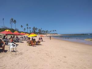 a group of people sitting on a beach with umbrellas at Casa Arembepe com Piscina in Camaçari