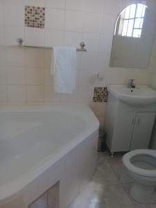 uma casa de banho branca com um lavatório e um WC em Rest Shade Bed and Breakfast em Palapye
