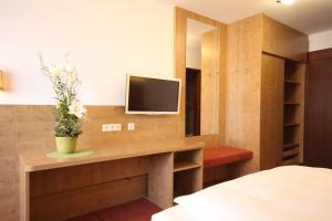 1 dormitorio con escritorio y TV. en Isar Hotel en Freising