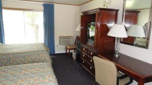 a hotel room with a bed and a desk with a television at Harbor Base Inn in Newport