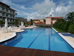 a pool at a resort with chairs and a building at Laguna Beach Porto in Porto De Galinhas