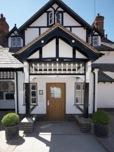 a white and black house with a brown door at Donington Park Farmhouse Hotel in Castle Donington