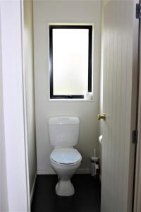 a bathroom with a white toilet and a window at Cozy Home in Rotorua