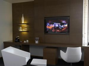 a living room with a tv and white chairs at Hotel Le Germain Calgary in Calgary