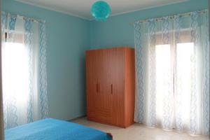 um quarto com um armário de madeira e 2 janelas em Casa Michelina em Belvedere Marittimo