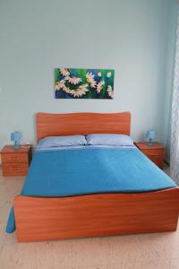 a bedroom with a wooden bed with a blue blanket at Casa Michelina in Belvedere Marittimo