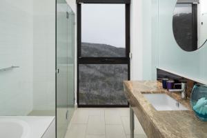 a bathroom with a shower, sink, and mirror at QT Falls Creek in Falls Creek