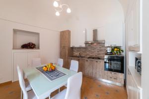 a white kitchen with a table and white chairs at L'Angolo dei Sogni in Ravello