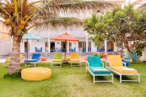 a group of chairs and umbrellas in front of a building at Hotel J Negombo in Negombo