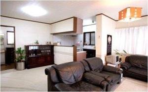 uma sala de estar com um sofá de couro e uma cozinha em Youyousanso Apartment in Mie em Tsu