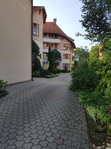 a house with a brick driveway next to a building at Napsugár Apartman in Balatonlelle