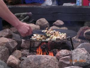 une personne qui cuisine de la nourriture sur un poêle au-dessus d'un feu dans l'établissement Föllingen Hotell, à Kisa