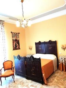 - une chambre avec un lit, une chaise et un lustre dans l'établissement Adeste 33, à Scicli
